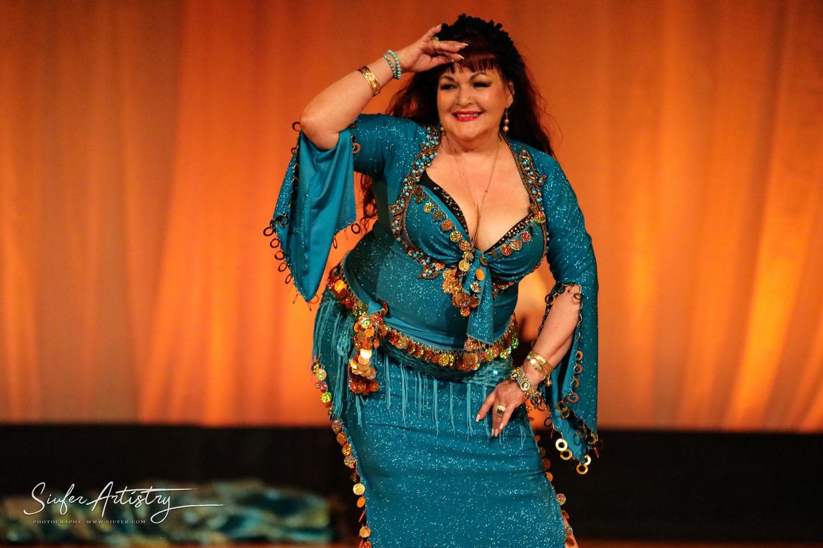 Jihan Jamal performing a hip circle in a teal costume at Arabian Voyage, 2019